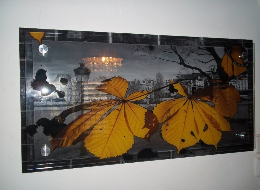 A glass wall decoration combines a city scene with autumn leaves across three layers.
